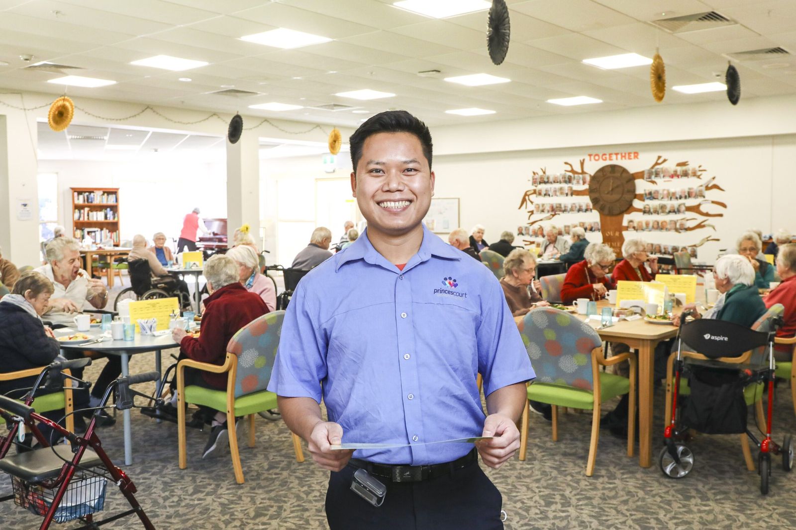 A staff member smiling in the busy dining room at lunchtime