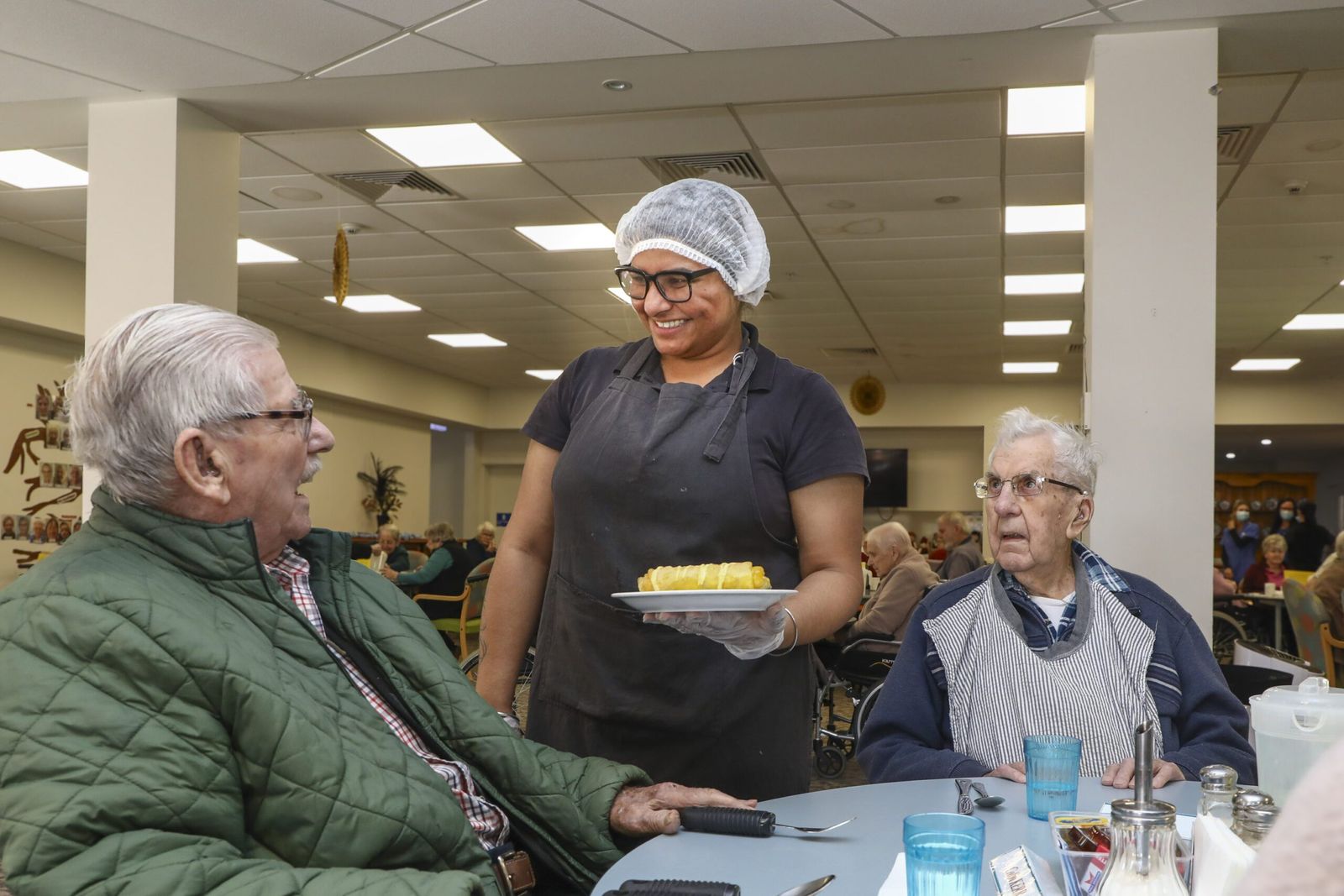Staff serving lunch to residents in the bright dining room
