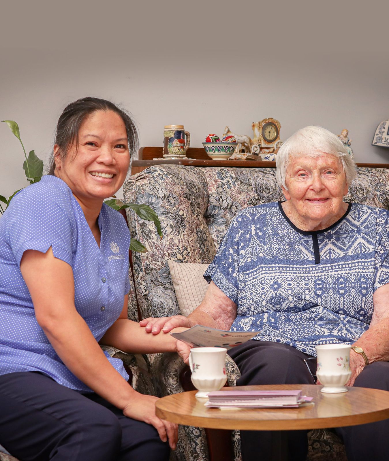 A Princes Court carer chatting with a client on her couch at home