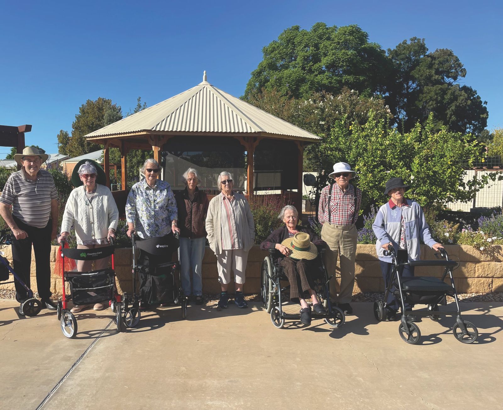 A group of residents and staff on an outing in a sunny park